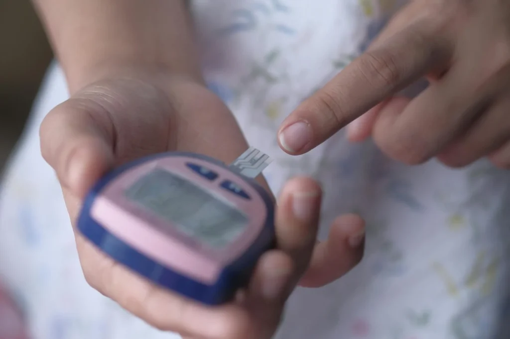 Chú cao niên người Việt ở Houston đo đường huyết tại nhà — insulin được giới hạn $35/tháng theo luật mới Part D 2026
