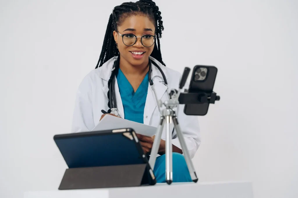 Một người Việt cao niên ở Houston ngồi tại nhà nói chuyện với bác sĩ qua cuộc gọi video trên máy tính bảng — khám bệnh từ xa (telehealth) với Medicare
